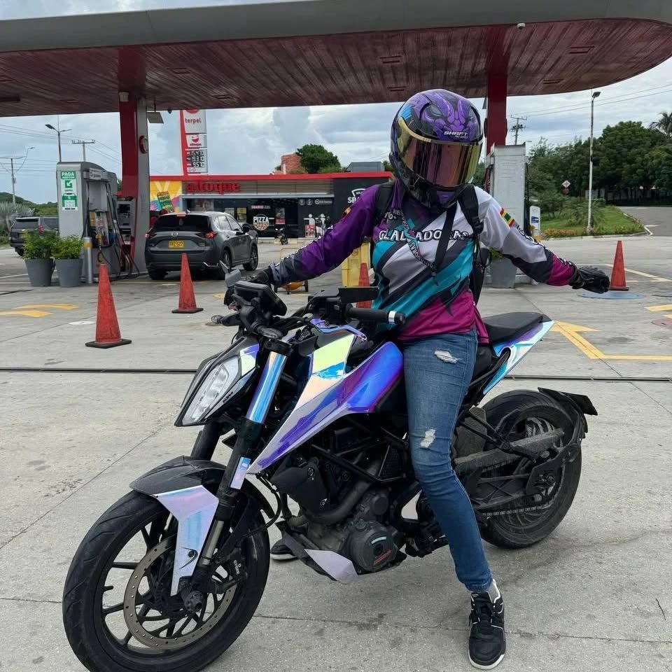 Motociclista con camiseta morada sobre su moto